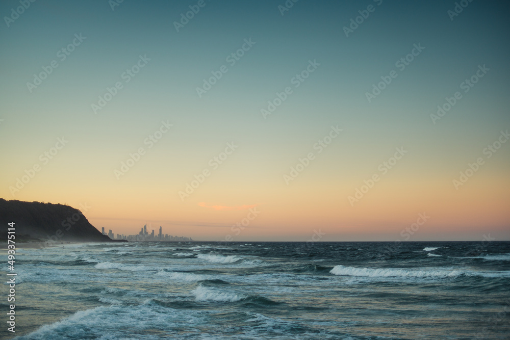 Sea waves and city skyline during sunset Sea waves and city skyline during sunset