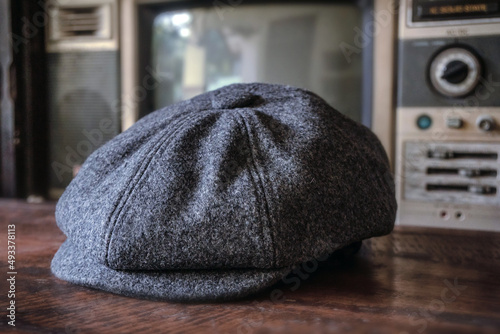 Detail of a classic eight-panel newsboy hat in tweed fabric herringbone in midnight black on a classic electronic background photo