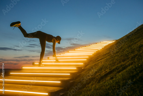 A woman kneads her body on the steps with illumination