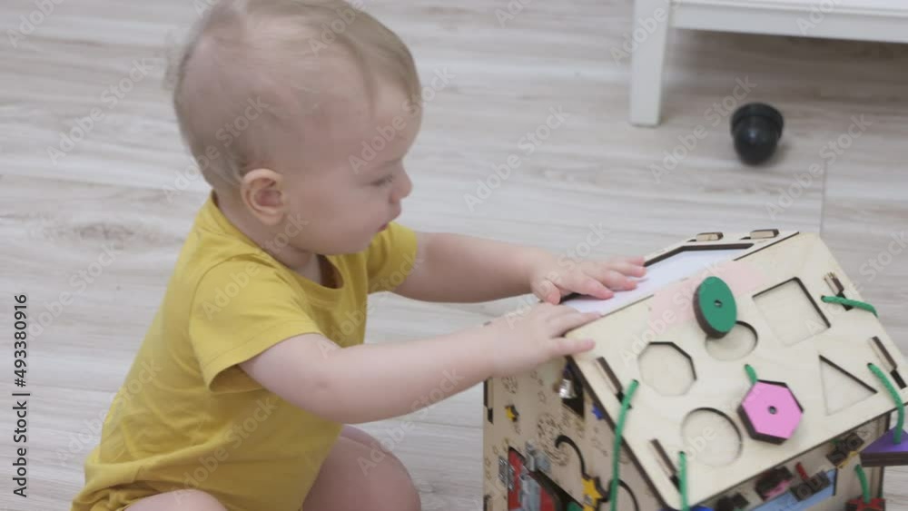 Child having fun playing with wooden busy board, happy kid play with educational learning toy enjoy leisure activity at home. High quality 4k footage