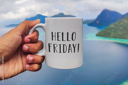 Friday greeting on white coffee or tea cup in hand on sea background. Hello Friday