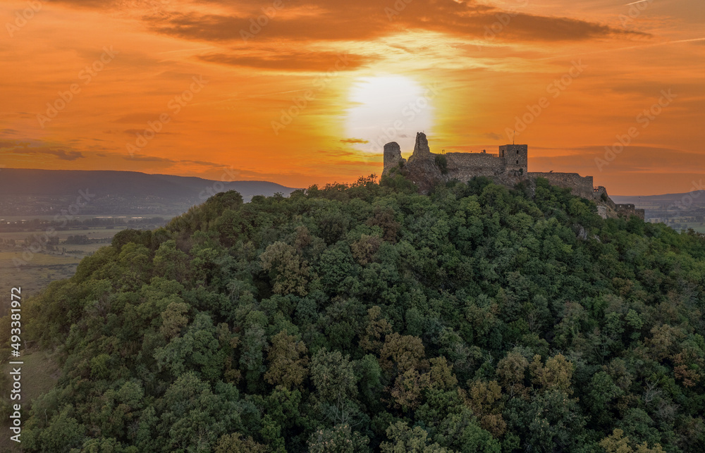 Aerial view of Szigliget castle above lake Balaton against the orange colors of the setting sun
