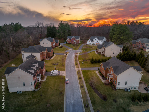 Colorful orange evening sun is setting over upper class East Coast American neighborhood cul-de-sac dead end street
 with large single family homes with big real estate lots and brick front photo