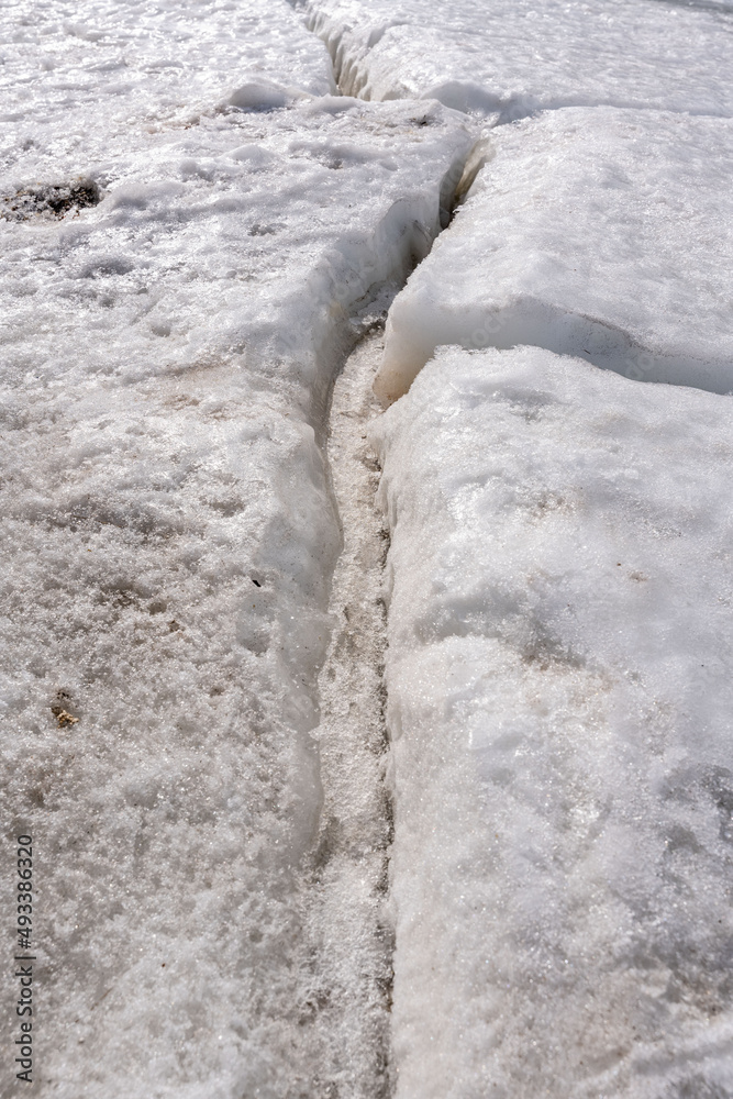 Fototapeta premium Large crack in permafrost ice revealing dry rocks hidden beneath.