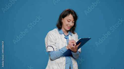 Female scientist taking notes on clipboard documents, writing formula results for chemistry analysis. Chemcial researcher using papers to do laboratory experiment for science study. photo