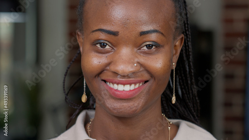 Portrait of african american woman looking at camera  wearing makeup and red lipstick. Young adult feeling happy and cheerful  showing positive natural facial expressions. Candid smile.