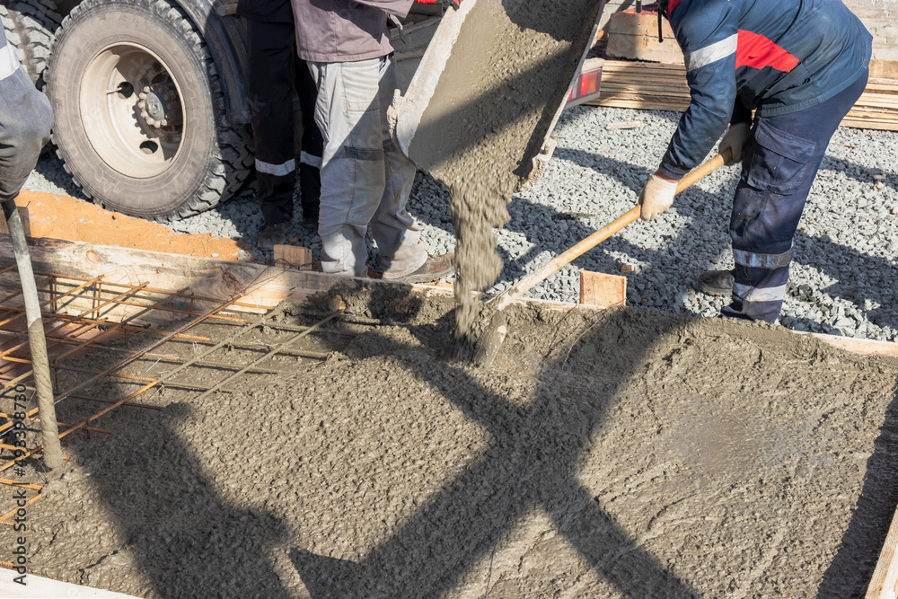 Pouring cement or concrete with a concrete mixer truck, construction site with a reinforced grillage foundation. Workers settle and level the concrete in the foundation. Pouring cement or concrete with a concrete mixer truck, construction site with a reinforced grillage foundation. Workers settle and level the concrete in the foundation.