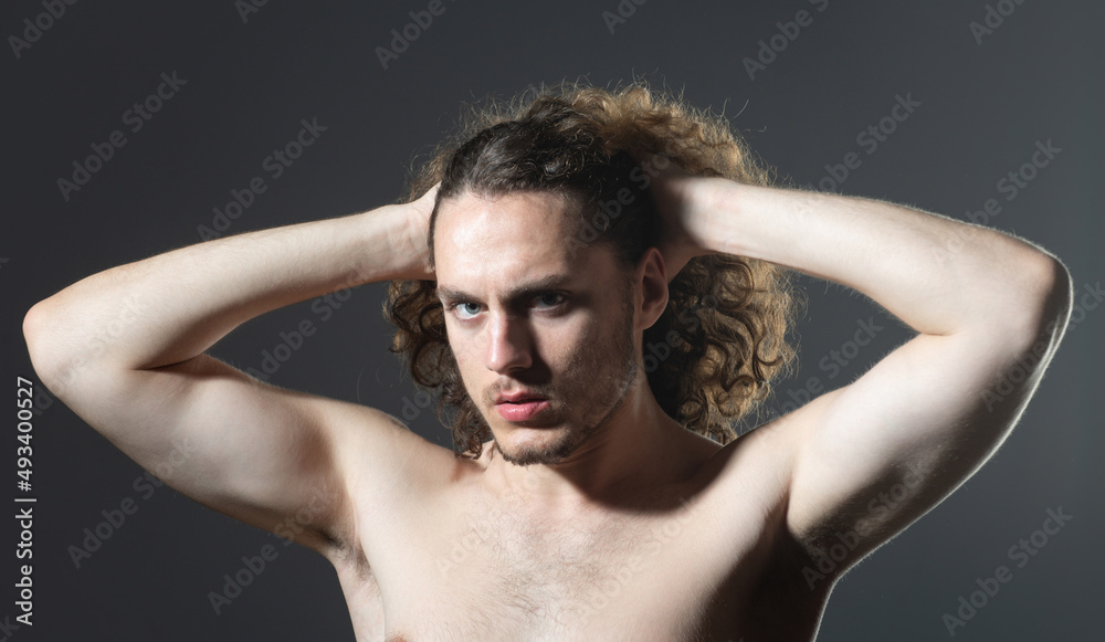 Young man with curly hair. Handsome man combing hair.