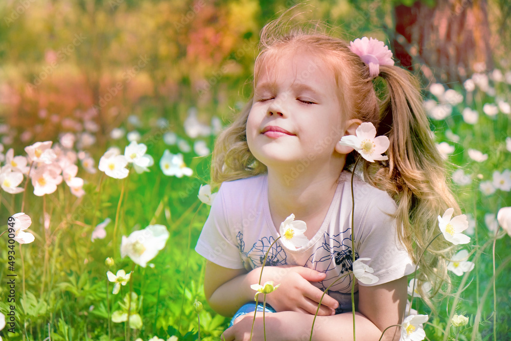 Little girl smelling anemone flower. Summer meadow. Happy child enjoying nature outdoors. Little girl smelling anemone flower. Summer meadow. Happy child enjoying nature outdoors.
