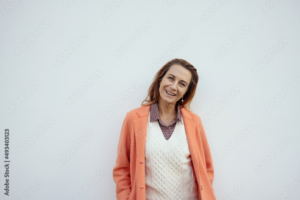 Portrait of mature woman laughing against grey background. Successful middle aged woman with toothy smile looking at camera. Cheerful happy beautiful lady smiling with copy space.