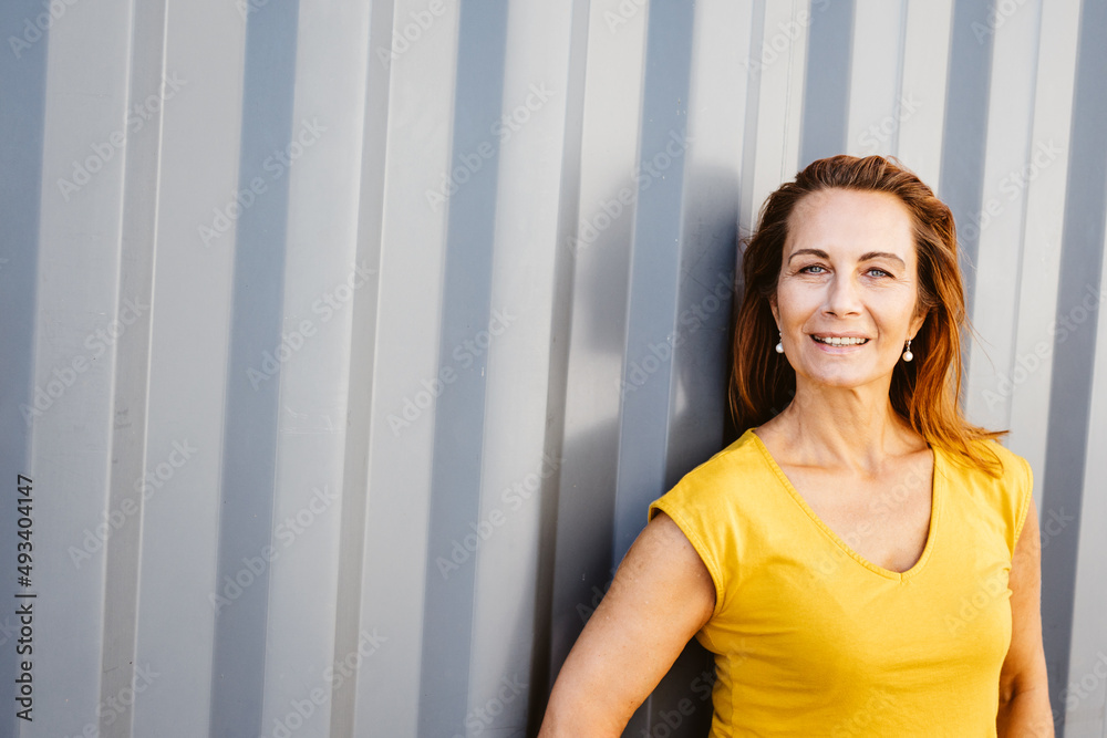 elder woman leaning against gray metal wall with copy space elder woman leaning against gray metal wall with copy space