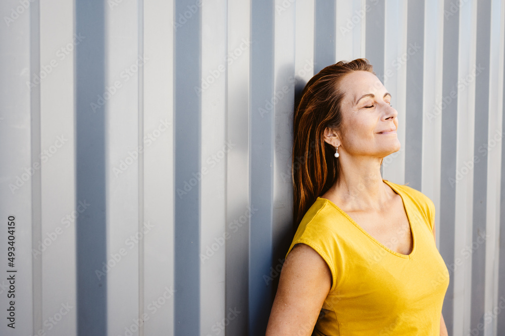 elder woman leaning against gray metal wall with copy space elder woman leaning against gray metal wall with copy space