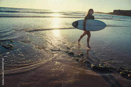 Young beautiful woman with long blonde hair going surfing in summer wearing swimsuit.