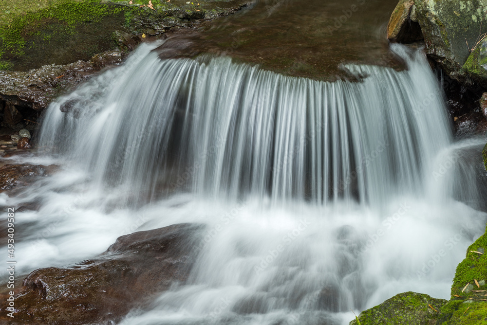 Fototapeta premium 岩の段差を落ちて飛沫を上げる川の流れ