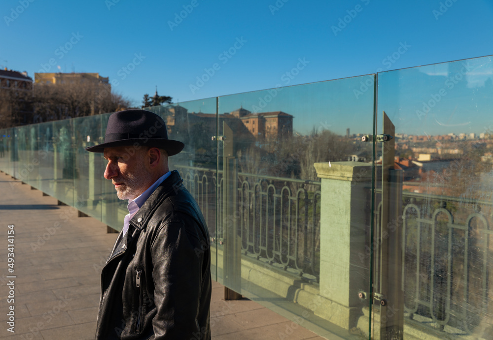 Adult man in hat and leather jacket walking on street. Madrid, Spain