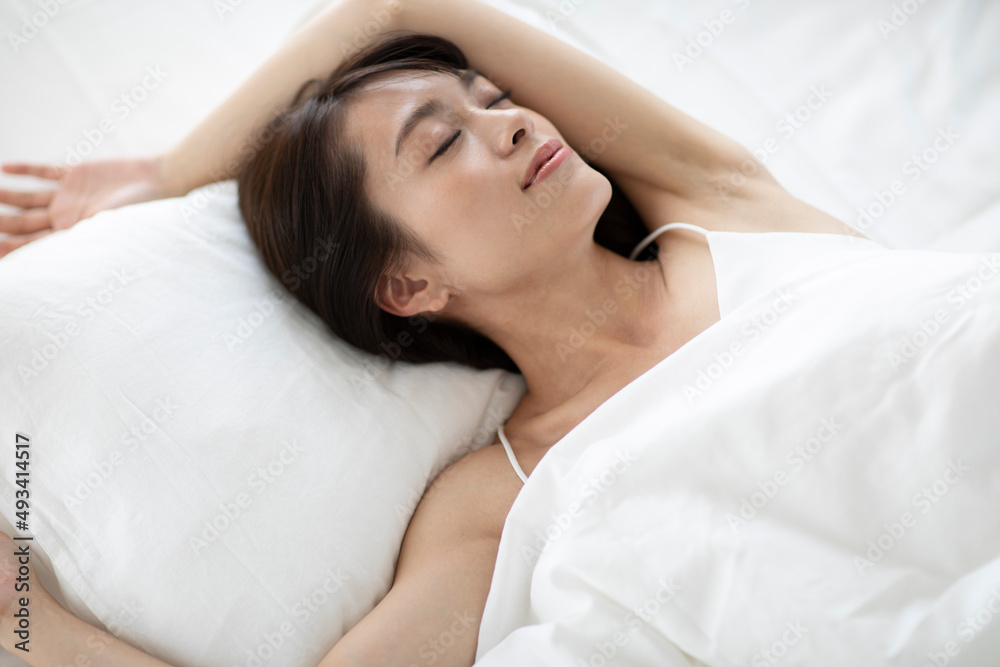ベッドで気持ちよさそうに寝る女性 ベッドで気持ちよさそうに寝る女性
