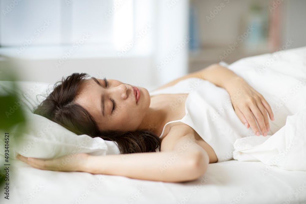 ベッドで気持ちよさそうに寝る女性 ベッドで気持ちよさそうに寝る女性
