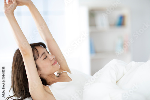 ベッドで伸びをする寝起きの女性 photo