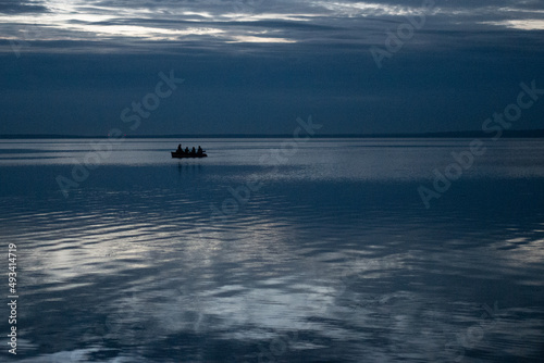 Boat with people at night on the lake against the sky
