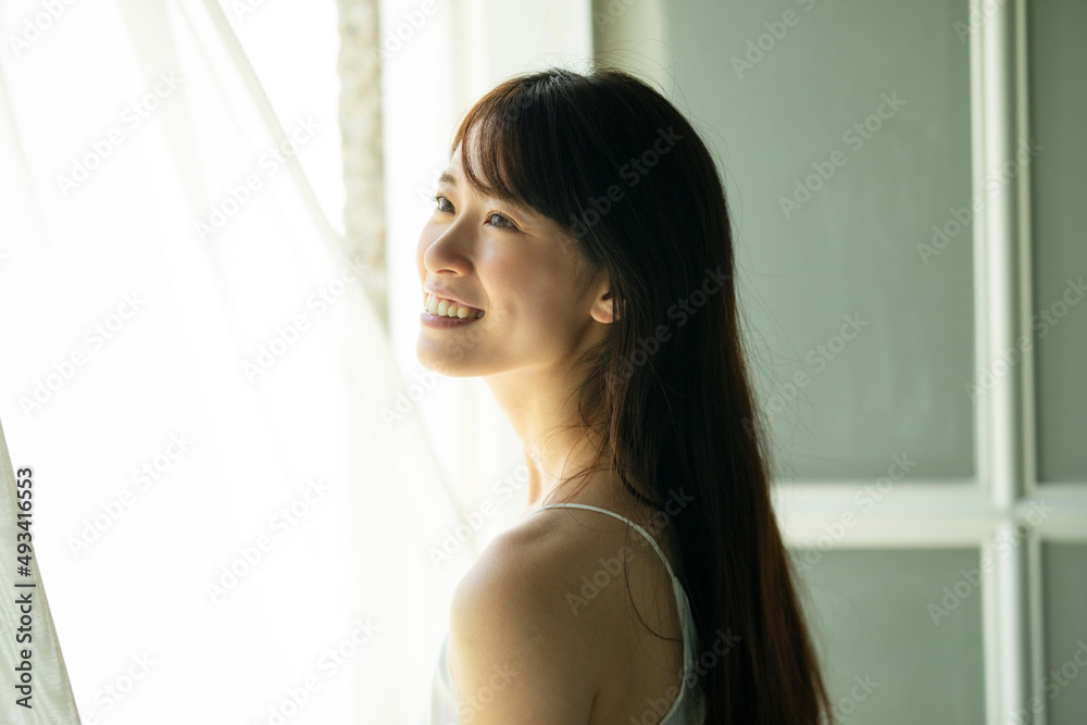 窓際で窓の外を見つめる女性 窓際で窓の外を見つめる女性