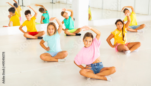 Children sitting and exercising ballet moves during their group training.