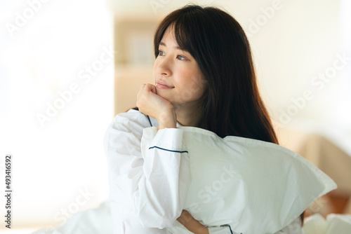 ベッドの上で枕を抱く女性