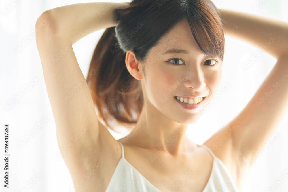 部屋で髪の毛を結ぶ笑顔の女性 部屋で髪の毛を結ぶ笑顔の女性