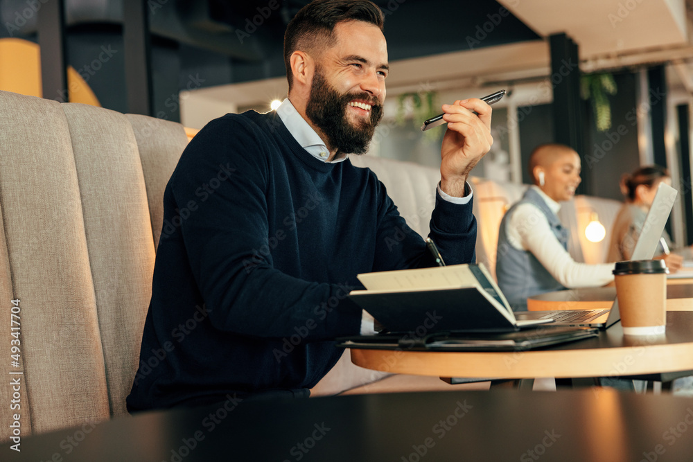 Cheerful businessman taking a phone call in a co-working space Cheerful businessman taking a phone call in a co-working space