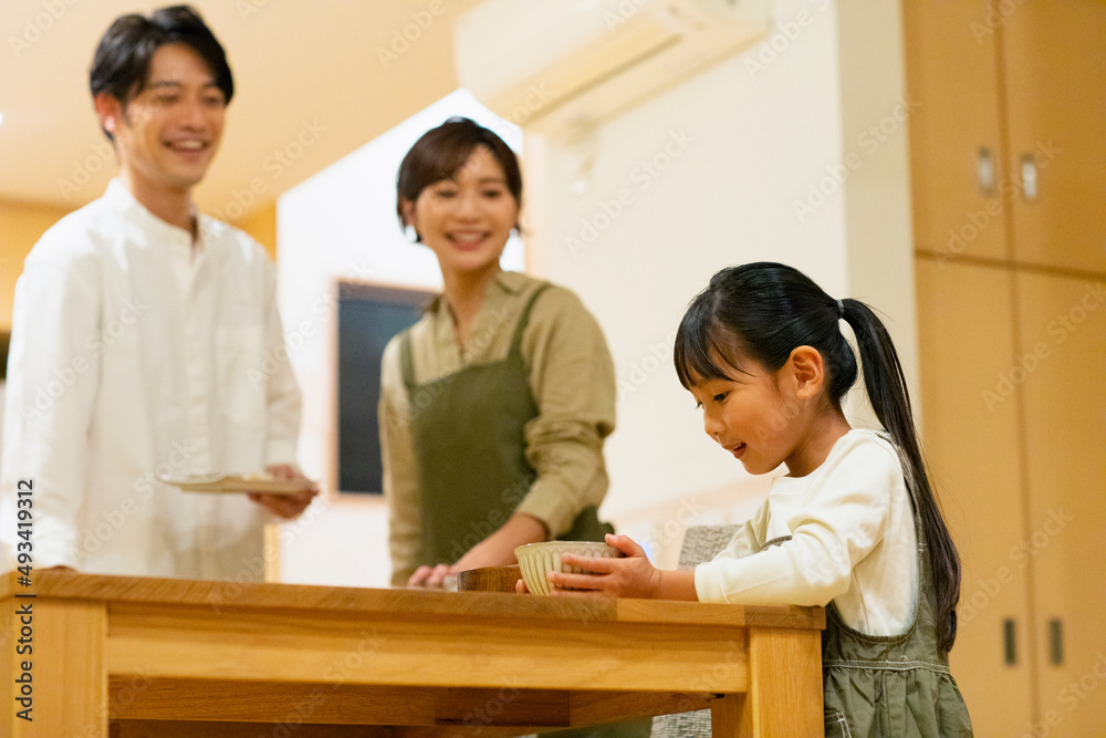 料理を配膳する子供と見守る家族 料理を配膳する子供と見守る家族