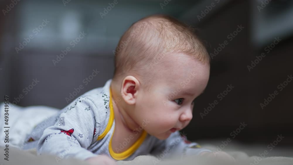 Toddler boy stays up and tries to hold his head up. Cute little kid looking around. Close up. Blurred backdrop. Toddler boy stays up and tries to hold his head up. Cute little kid looking around. Close up. Blurred backdrop.