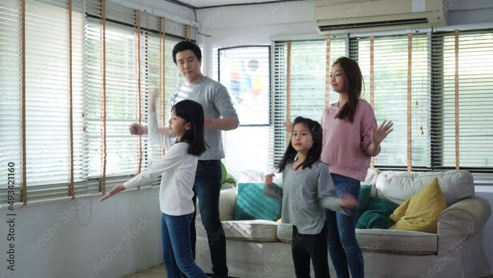 Asian family dancing together in living room at home. Father and daughter enjoyment with music while being celebration at home. Leisure activity stay at home of happy family.
