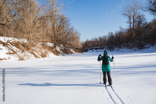 A skier walks in the snow in the forest against the background of the sky. An active lifestyle, winter sports, a person with a backpack on his back, a tourist on a hike.