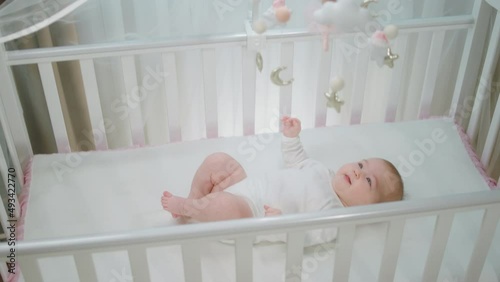 Wallpaper Mural Charismatic pretty baby girl playing with her cot toys while laying down in her baby cot concept of childhood and maternity Torontodigital.ca