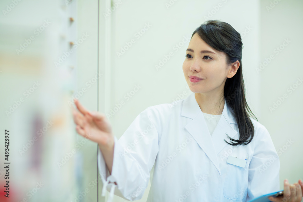 棚から薬をとる女性薬剤師