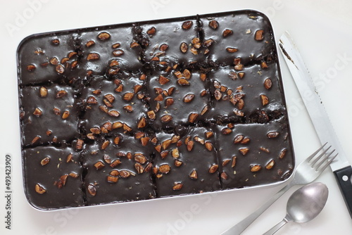 Slicing of Texas sheet cake. Buttery and chocolaty cake sliced to rectangular pieces inside the baking bin. Fresh from Oven