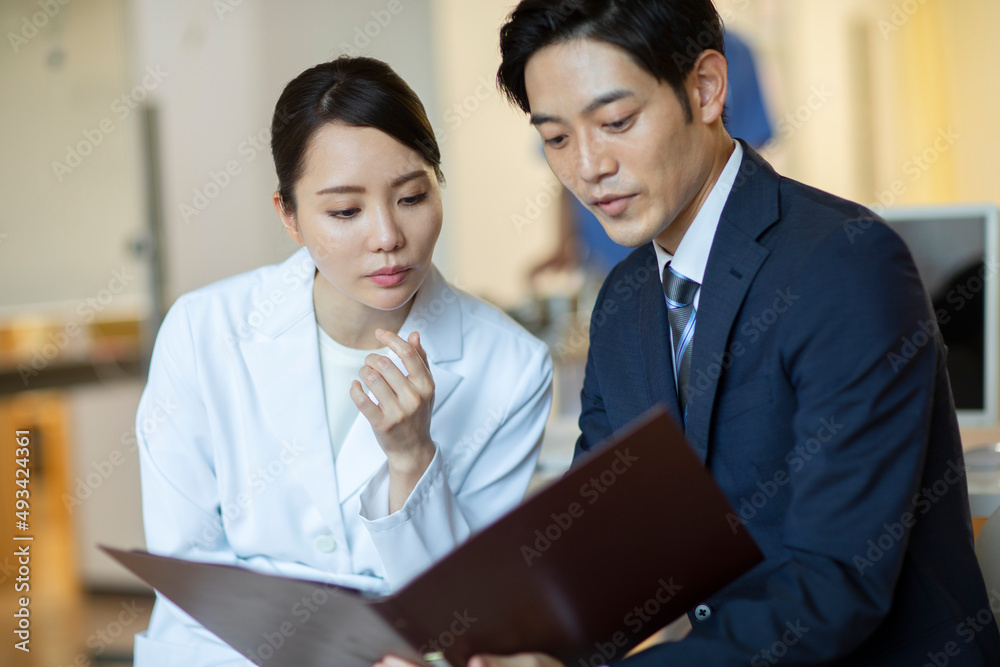 打ち合わせをするビジネスマンと女医