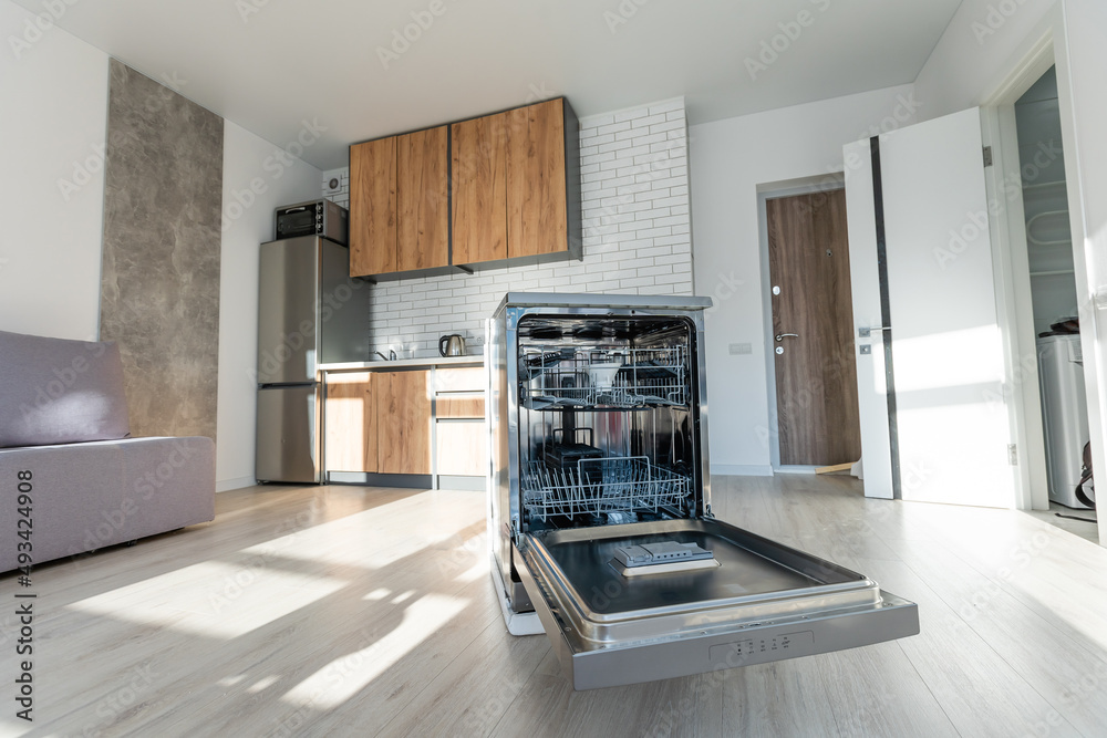 An empty dishwasher, opened, in the modern kitchen of a home. An empty dishwasher, opened, in the modern kitchen of a home.