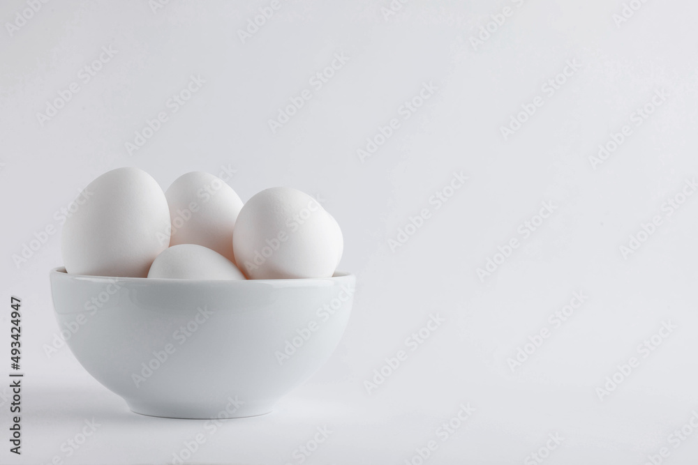 Chicken white fresh eggs from free-range in egg cups with natural feathers on light background. Concept farm products and natural nutrition, rural and healthy dairy products Copy space or empty place Chicken white fresh eggs from free-range in egg cups with natural feathers on light background. Concept farm products and natural nutrition, rural and healthy dairy products Copy space or empty place