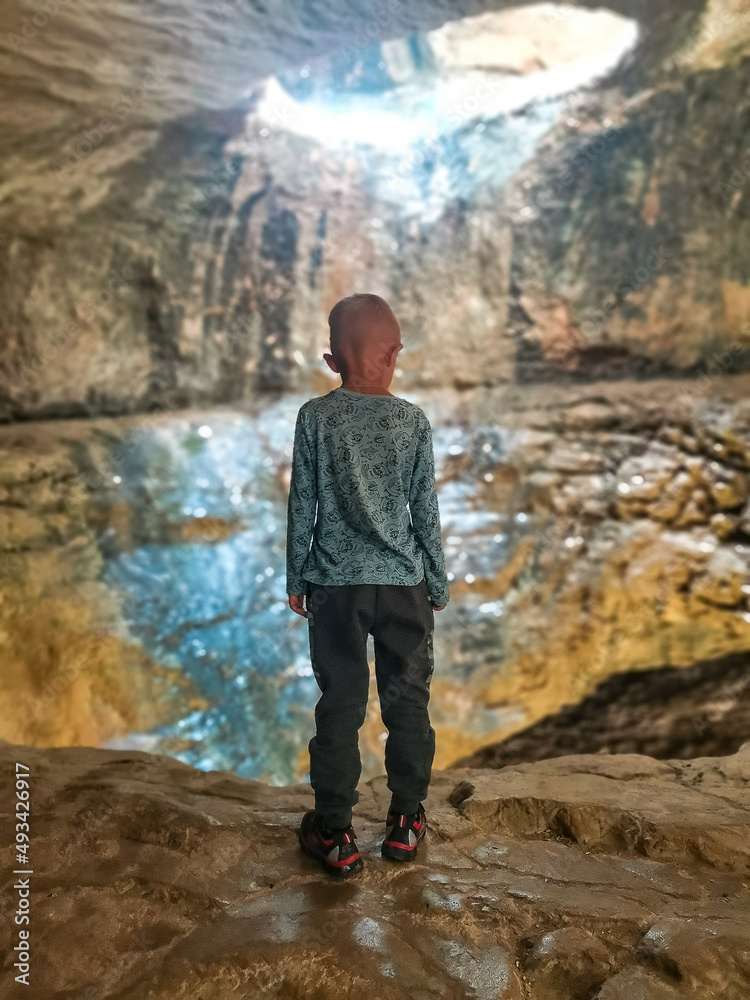 A boy on the background of a view of the dried-up Saltinsky waterfall. Russia, Dagestan, June 2021.