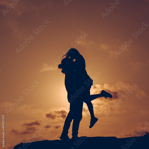 Silueta de novios a contraluz al atardecer besándose y divirtiéndose. 
Concepto, amor de pareja, recién casados.  photo