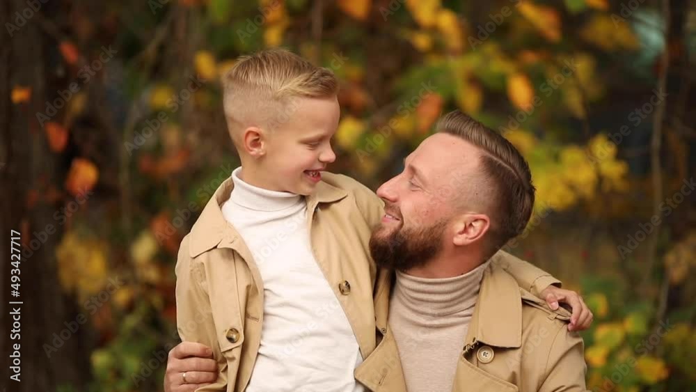 Dad and son are walking in the park. Son and dad laugh merrily. Family values. The concept of a happy family. Dad and son are walking in the park. Son and dad laugh merrily. Family values. The concept of a happy family.
