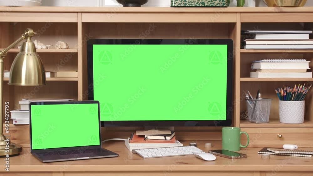 Desktop and Laptop Computers with Green Screen in Home Office Interior