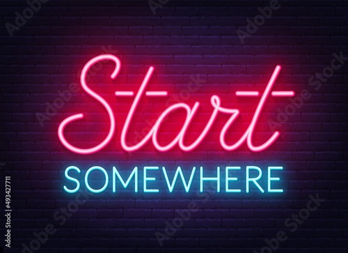 Start Somewhere neon sign on brick wall background.