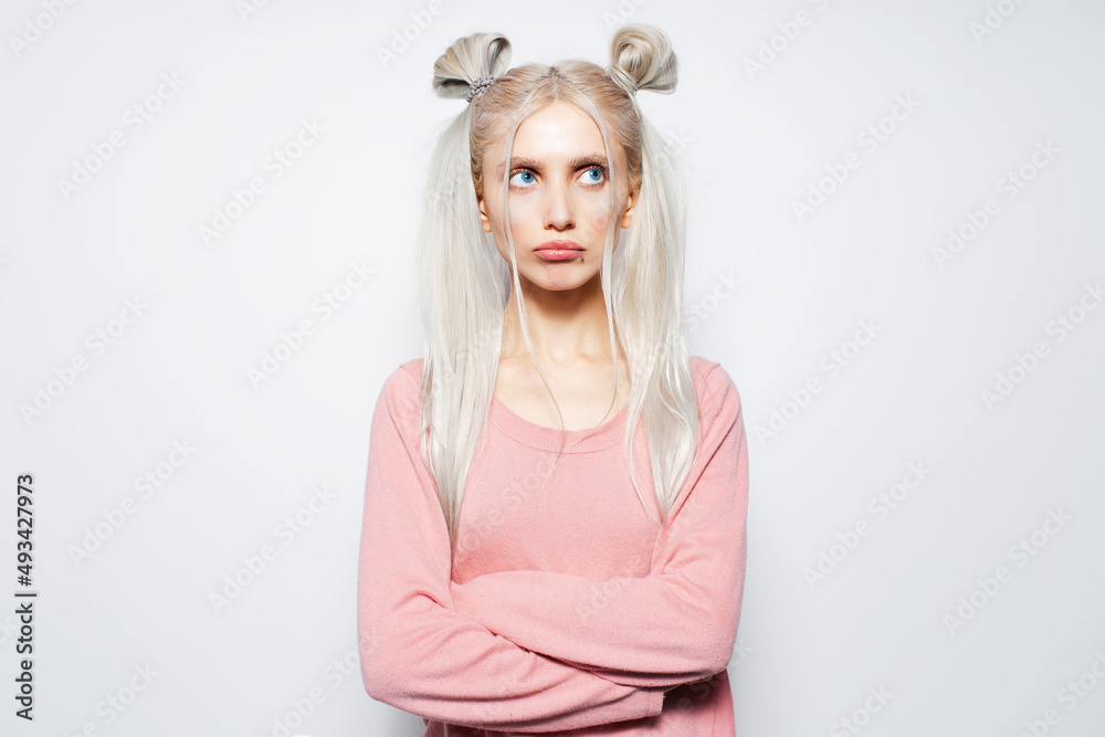 Studio portrait of offended, pretty blonde girl with two hair buns, on white. Studio portrait of offended, pretty blonde girl with two hair buns, on white.