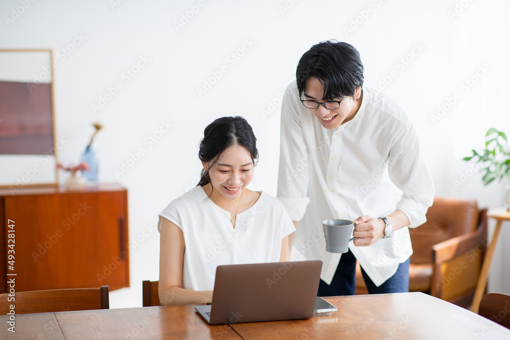 屋内でパソコンをしながら会話をするカップル