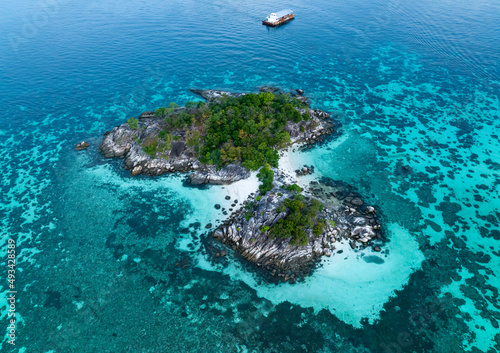 Above view of the Tropical island beach with seashore as the tropical island in a coral reef ,blue and turquoise sea with local boat background