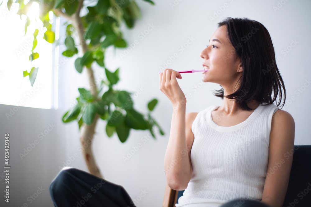 ソファーで歯を磨く女性