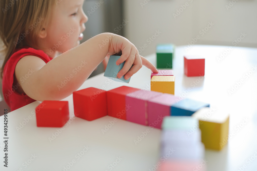 child playing and building with colorful wooden toy bricks on white wooden table. Early learning and development child playing and building with colorful wooden toy bricks on white wooden table. Early learning and development