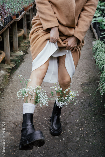 Woman legs in boots with flowers in socks walks in greenhouse.	 photo