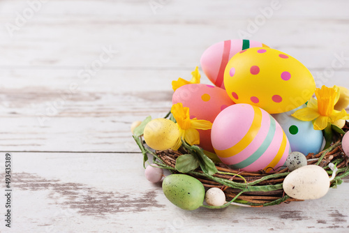 Multi coloured easter eggs in nest on wooden background. Happy Easter greeting card. Easter background.